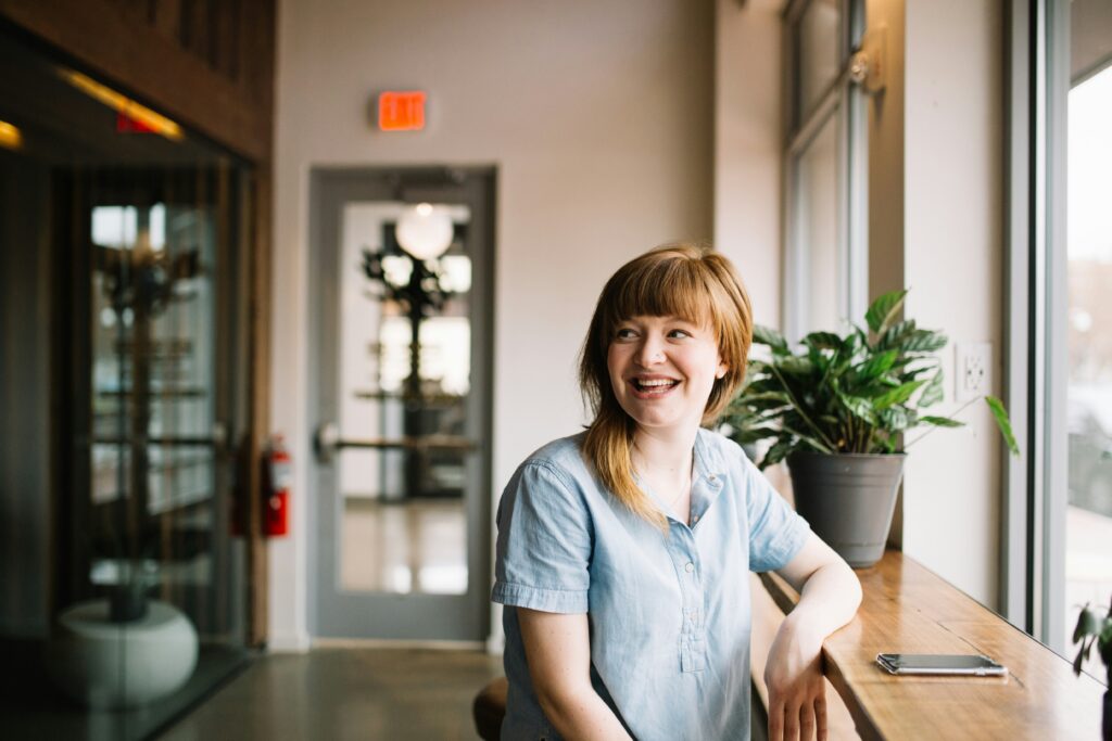Smiling woman near window, plant in office
