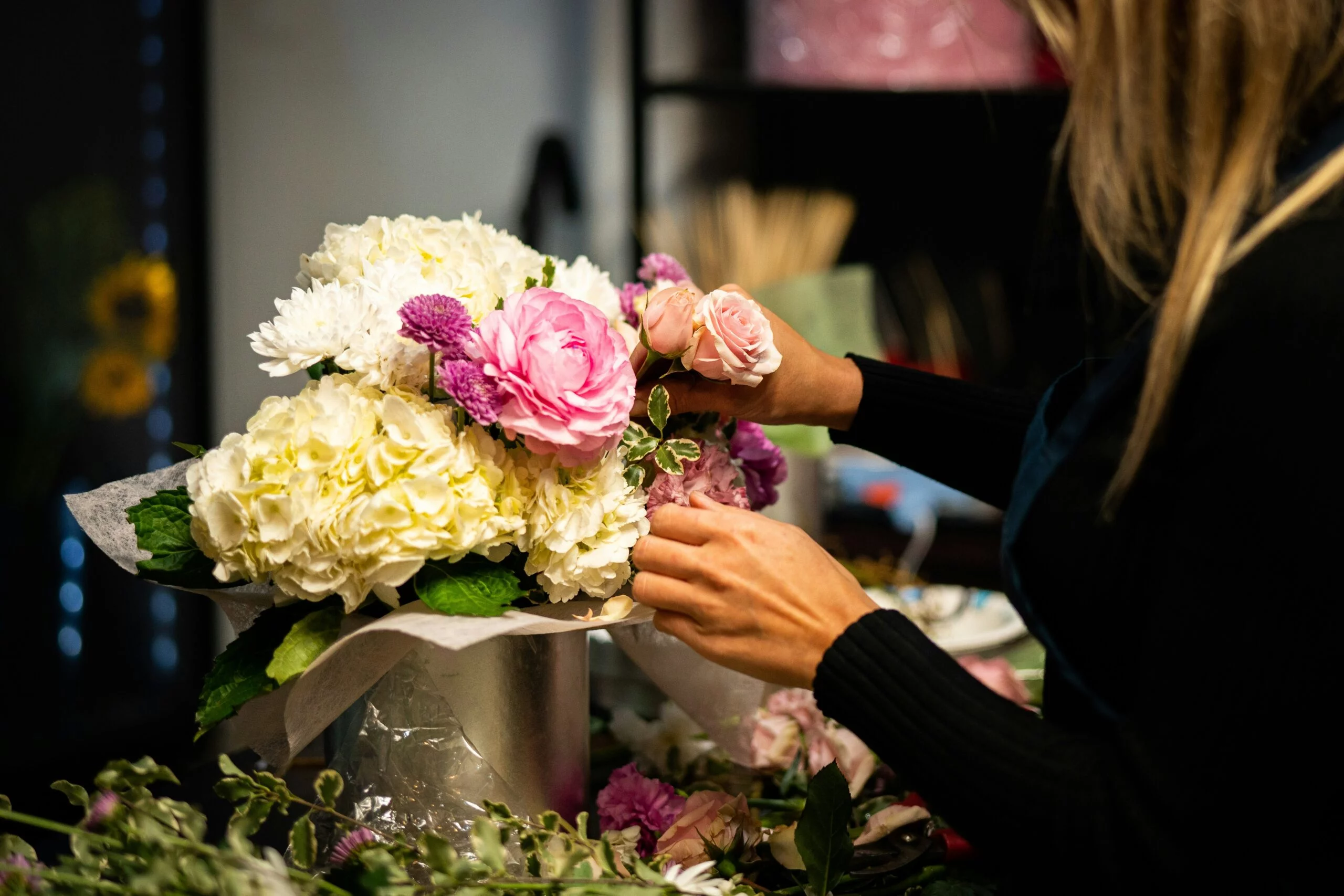 florist arranging hydrangeas, roses and peony flowers